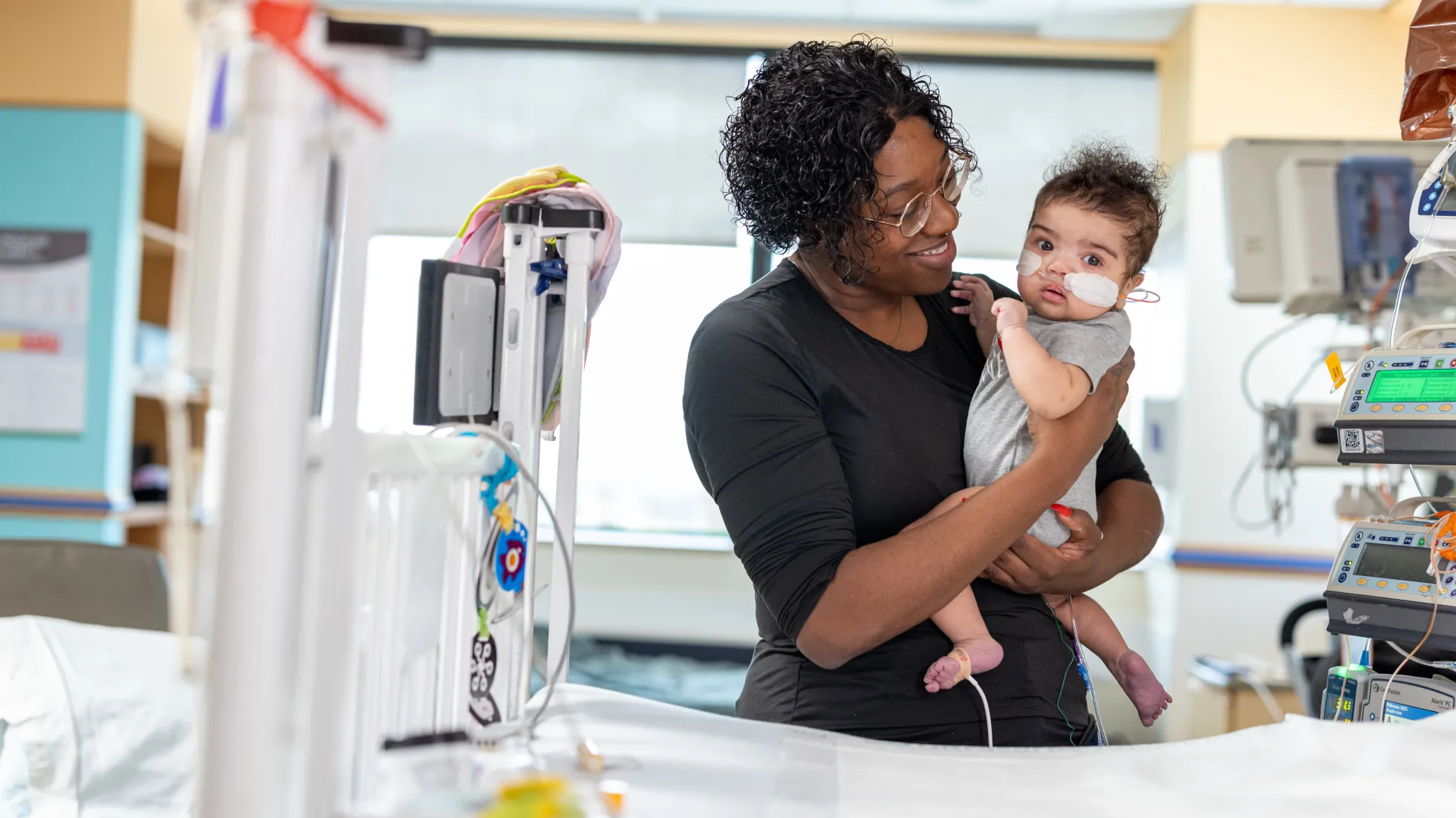 A mother holds her newborn baby proudly in a hospital room.