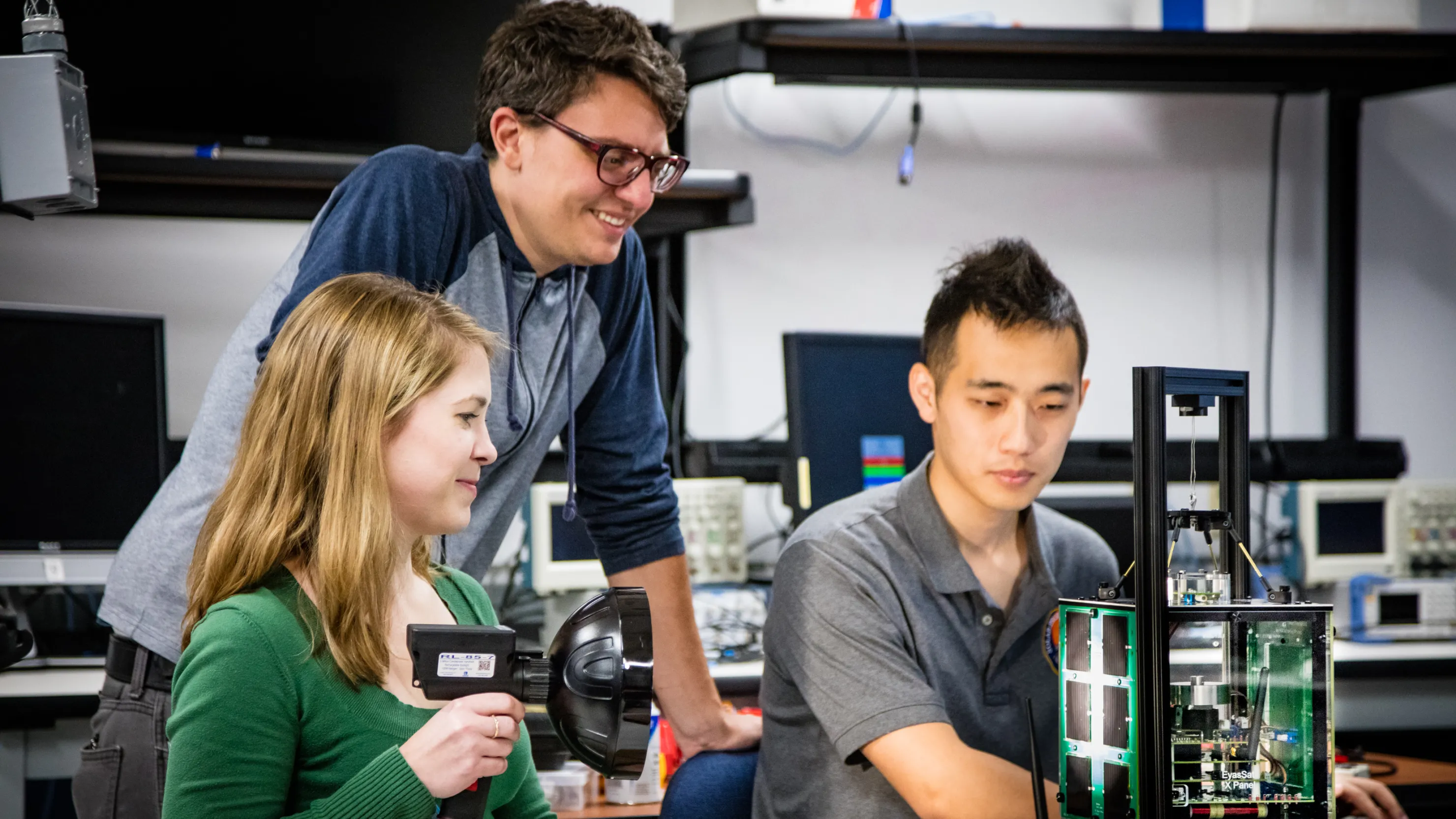 Three young scientists work together in a lab setting.