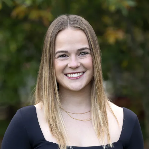 A professional headshot of Elle Wassertzug. She has long blonde hair and wears a black shirt.