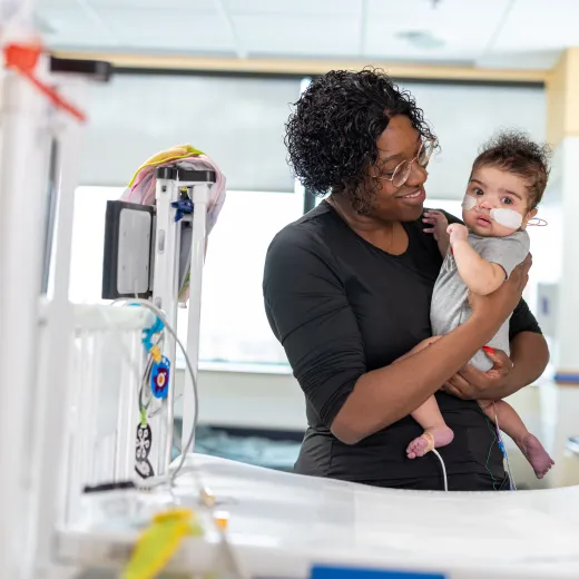 A mother holding and smiling at her baby in a hospital room.