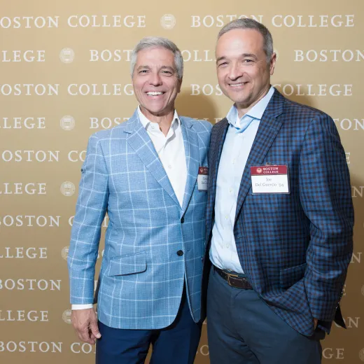 Carmen and Joe Del Guercio pose in front of a backdrop decorated with the Boston College logo.