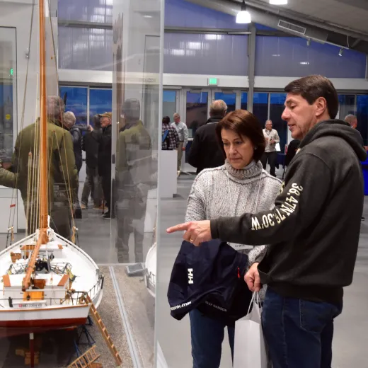 A woman and man view a detailed scale model of a historic boat in a museum exhibit.