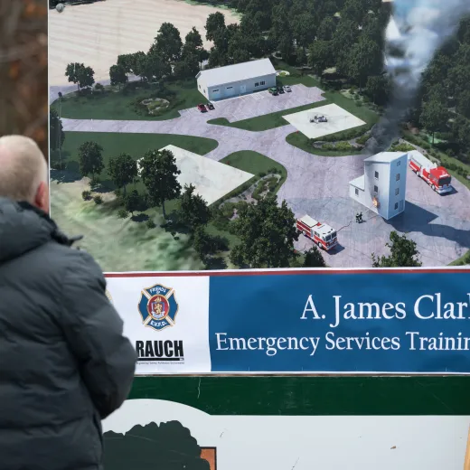 A man sits viewing signage displaying an architectural rendering of the A. James Clark Emergency Services Training Campus in Easton, Maryland.