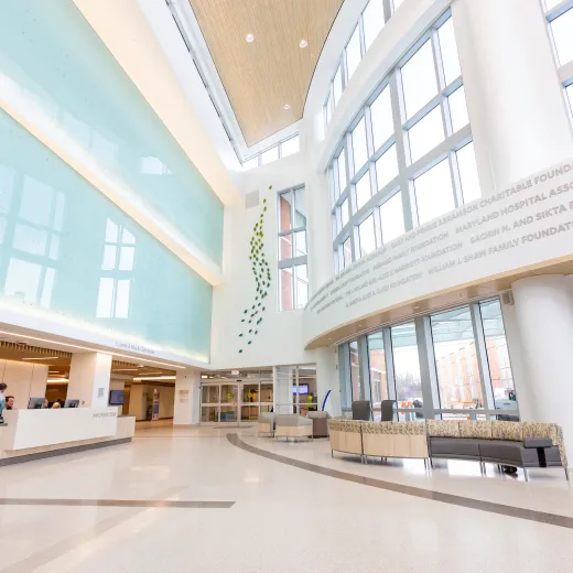 A welcoming hospital lobby with comfortable seating, a reception area, and natural light coming through large windows.