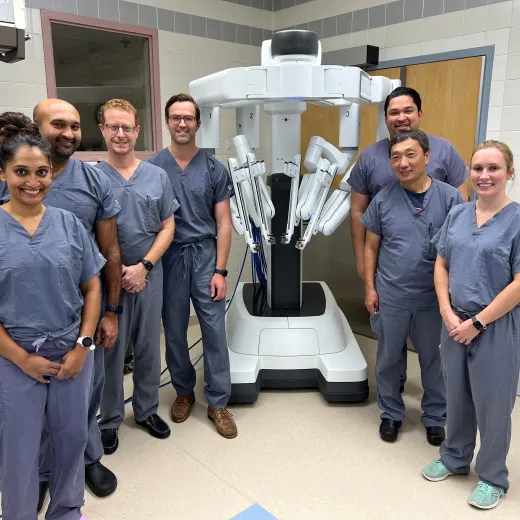 Medical professionals standing beside advanced equipment in a hospital setting.