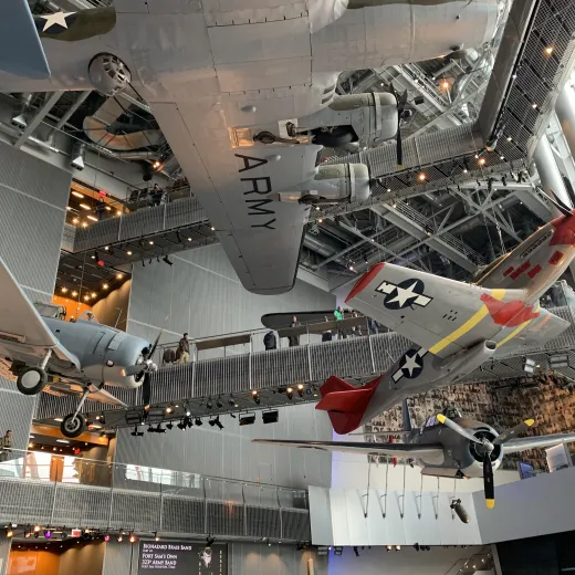 A collection of vintage World War II aircraft is suspended from the ceiling in the main gallery of the National WWII Museum.
