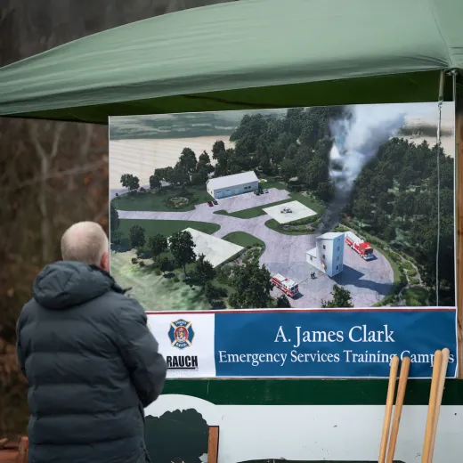 A man sits viewing signage displaying an architectural rendering of the A. James Clark Emergency Services Training Campus in Easton, Maryland.