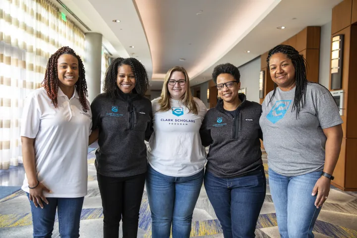 Five Clark Scholars Program Leaders stand in a group and smile. They all wear Clark Scholars Program attire.