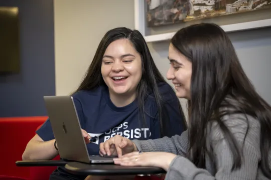 A DCPS Persists coach smiles at the computer while helping a DCPS student