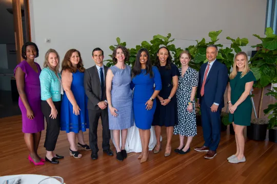 Ten members of the Clark Foundation staff stand in a row and smile at the camera. They are wearing business casual attire.