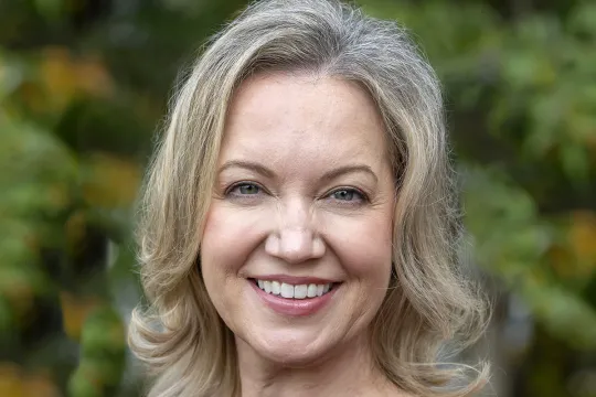 A professional headshot of Danielle Hamberger. She has blonde shoulder-length hair and wears a burgundy dress.