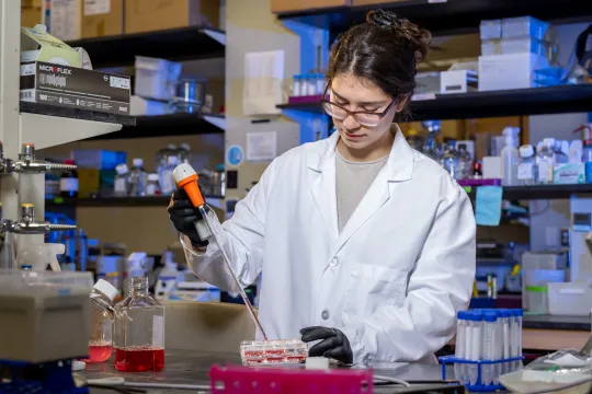 Vanderbilt Clark Scholar Yoanna Ivanova conducts research in a lab. She wears a lab coat and protective gloves.