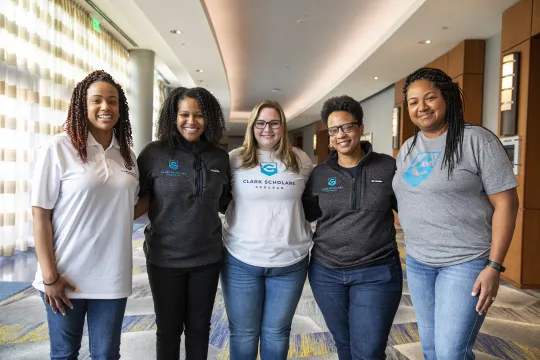Five Clark Scholars Program Leaders stand in a group and smile. They all wear Clark Scholars Program attire.