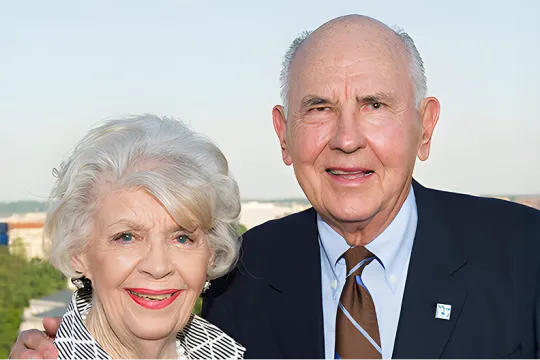 A. James and Alice B. Clark attend an outdoor celebration at GWU. The Kennedy Center and the DC skyline are in the background.