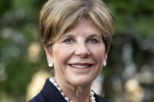 A professional headshot of Board Chair Courtney Clark Pastrick. She wears a blazer and a pearl necklace.