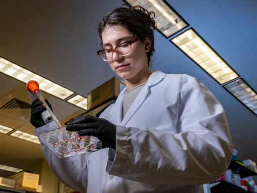 Vanderbilt Clark Scholar Yoanna Ivanova conducts research in a lab. She wears a lab coat and protective gloves.