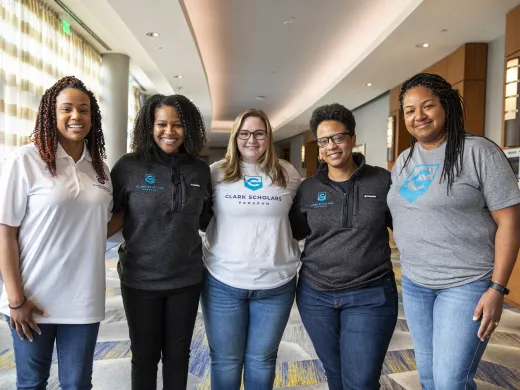 Five Clark Scholars Program Leaders stand in a group and smile. They all wear Clark Scholars Program attire.