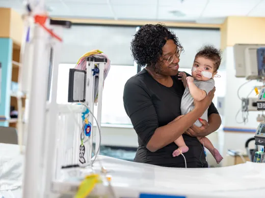 A mother holds her newborn baby proudly in a hospital room.
