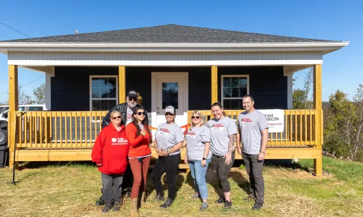 A group of Team Rubicon volunteers stand in front of a new house they helped construct.