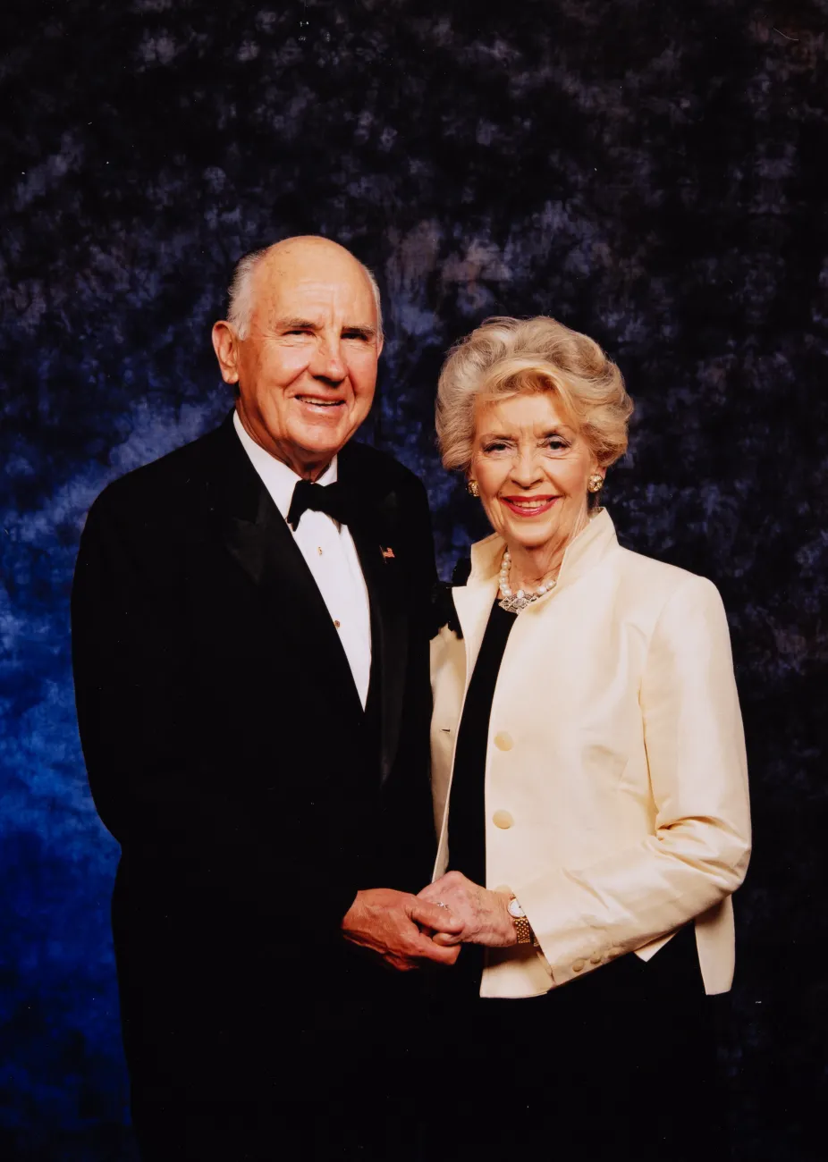 A. James and Alice B. Clark attend a black tie gala. They are in their seventies and hold hands while they pose.